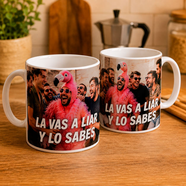Dos tazas personalizadas con una fotografía de un grupo de amigos y la frase «La vas a liar y lo sabes», impresas sobre tazas blancas de cerámica y presentadas sobre una encimera de cocina.